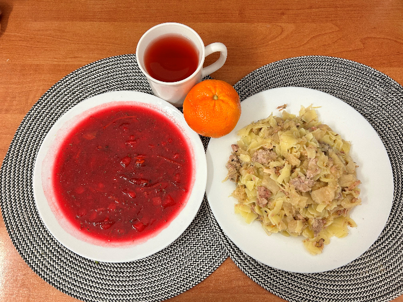 Na zdjęciu: Barszcz czerwony z botwinką i ziemniakami, Łazanki z kapustą i mięs wp z łopatki, Kompot owocowy, Mandarynka